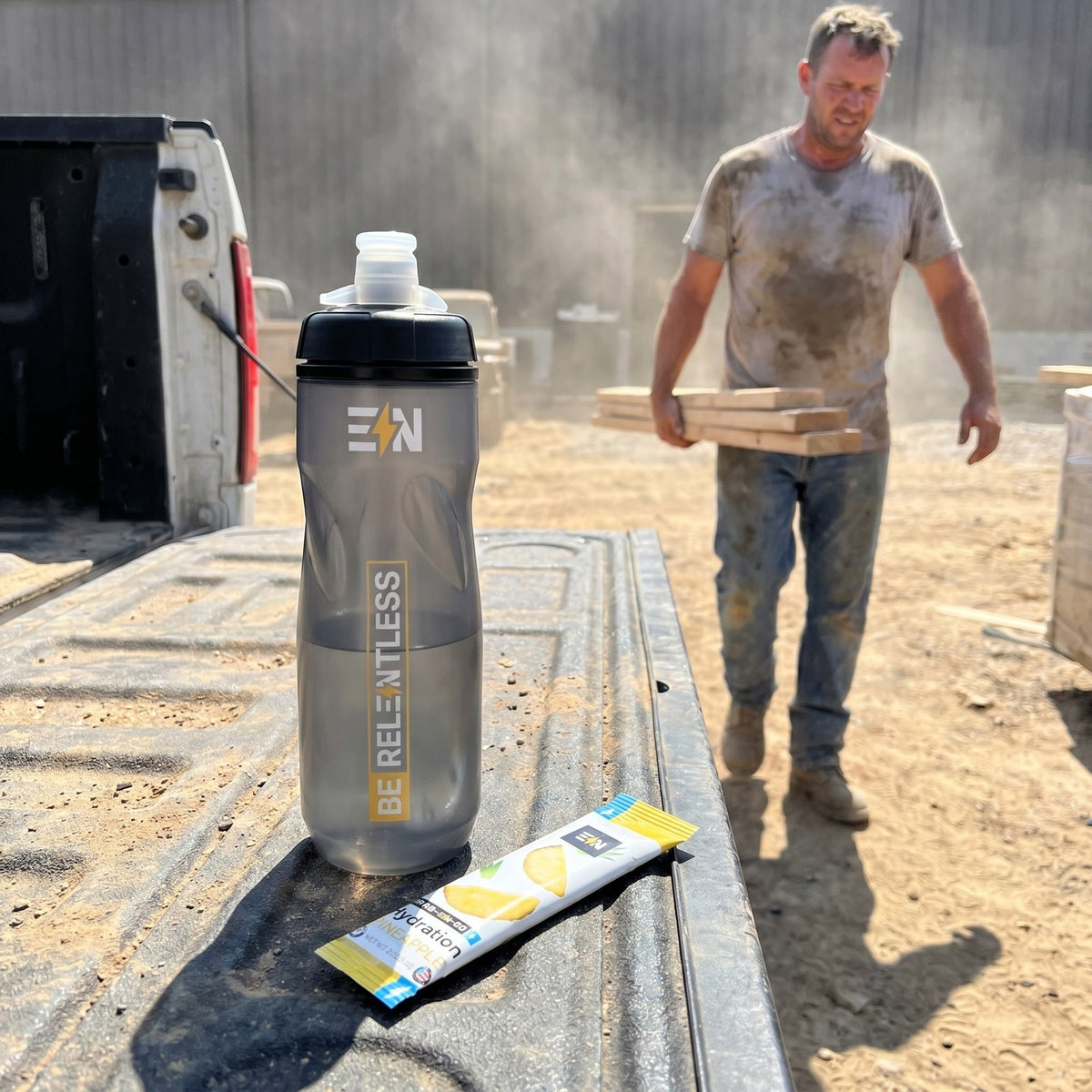 Engineered Nutrition squeeze bottle and Pineapple hydration stick on a truck tailgate at a dusty job site on a hot day
