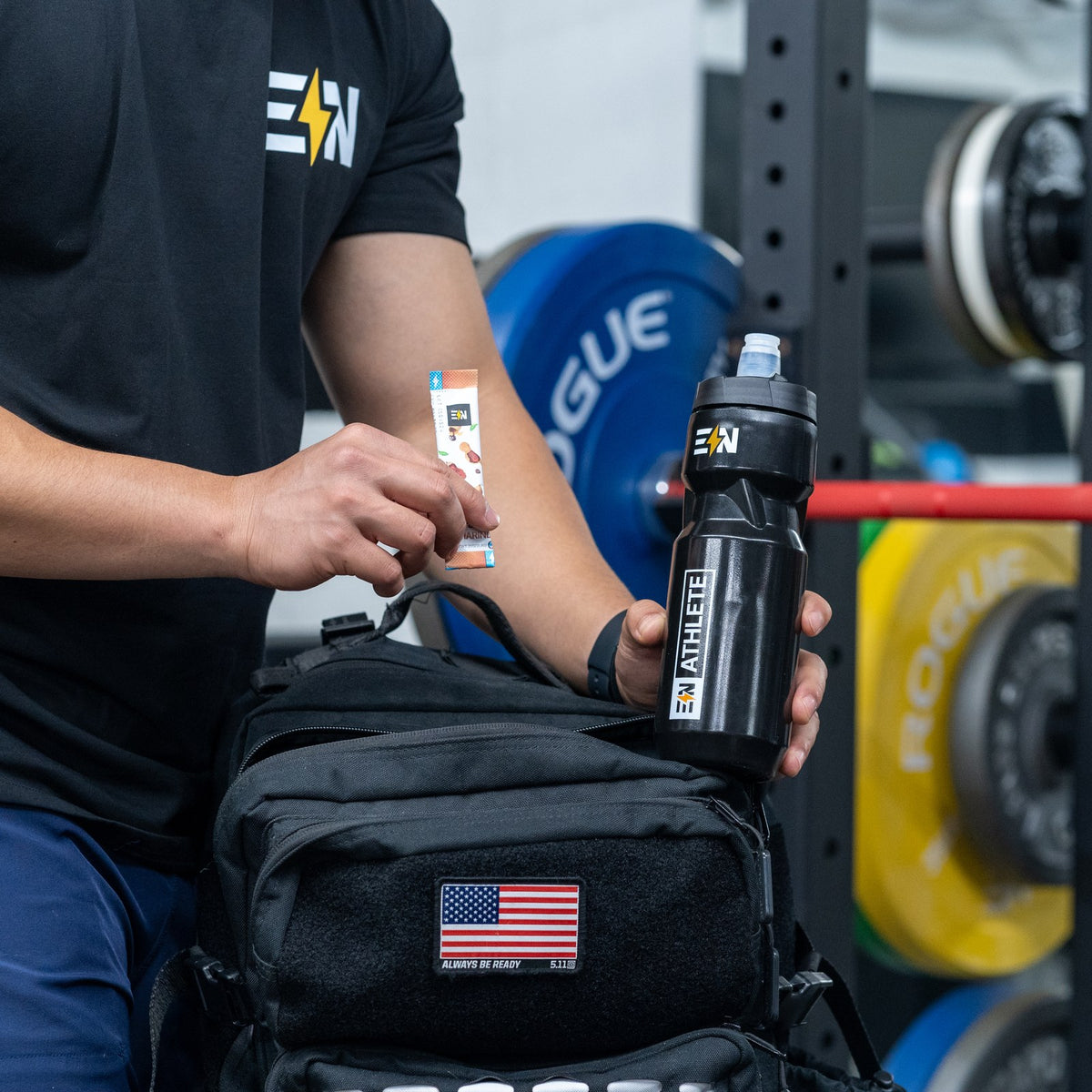 Athlete in an EN shirt mixing a hydration stick into an EN bottle at the gym