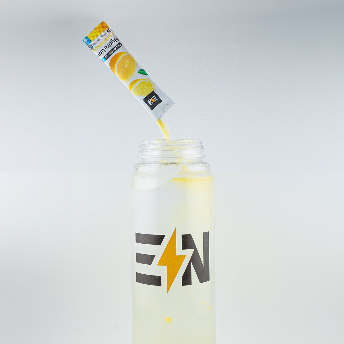 An Engineered Nutrition Lemonade hydration stick poured into a clear bottle of water