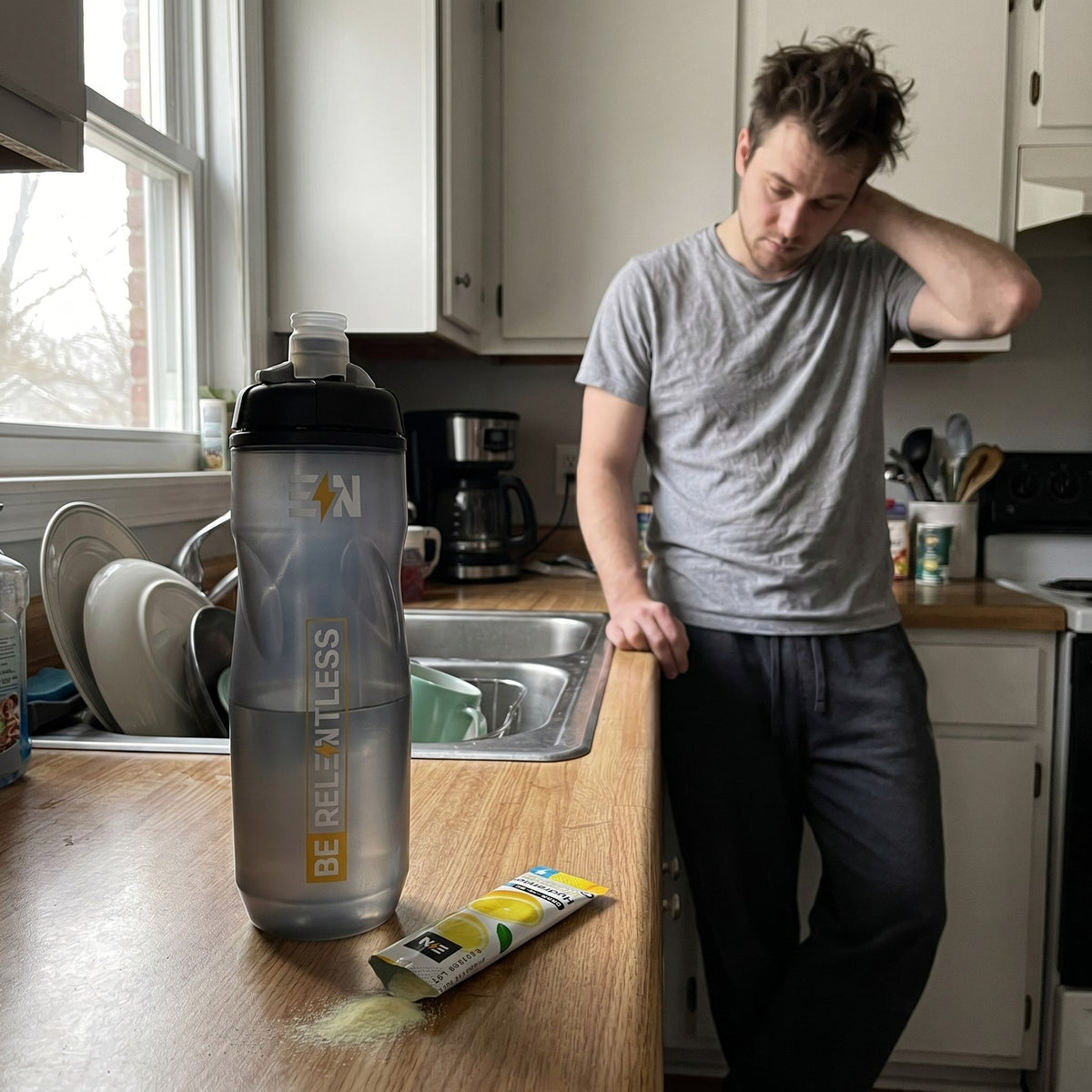 Engineered Nutrition squeeze bottle and a torn Lemonade hydration stick on a kitchen counter the morning after a late night